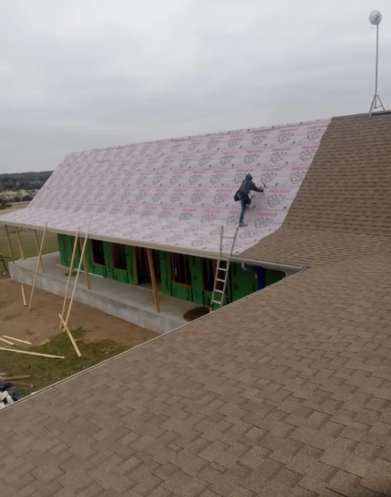 Worker preparing underlayment for a metal roof installation in Onalaska